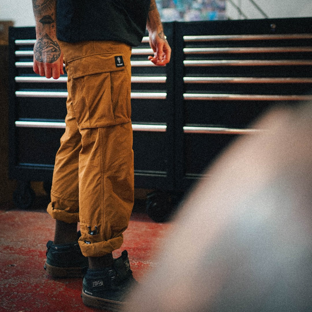 Person wearing mustard yellow pants and black shoes in a workshop setting